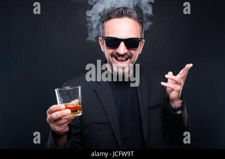 Stylish rich bearded man enjoying a brandy or whiskey looking excited as classy lifestyle concept Stock Photo