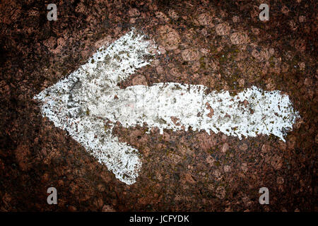 White arrow painted on a rock Stock Photo