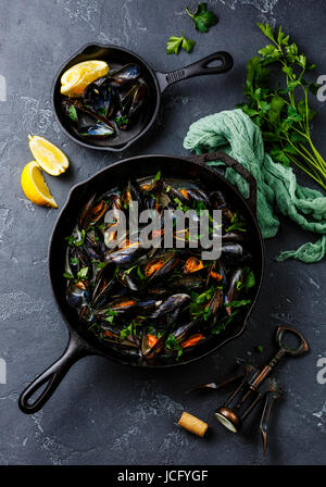 Mussels in black cooking pan with parsley on dark stone background Stock Photo