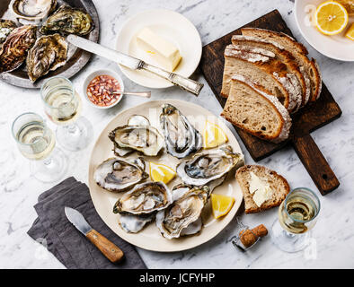 Open shucked Oysters with bread, butter and champagne on white marble background Stock Photo