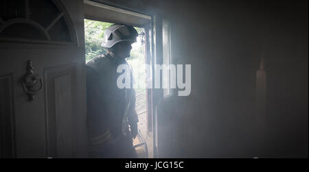 Fireman entering a smoke filled room in a domestic house. Stock Photo