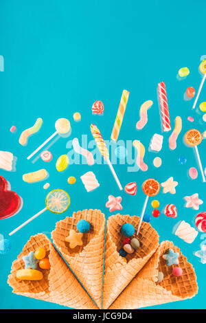 Close-up top view of waffle cones and mix of various sweets on blue background Stock Photo