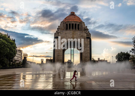 Girl playing with the water fountain in front of Monument to the Mexican Revolution (Monumento a la Revolucion) - Mexico City, Mexico Stock Photo