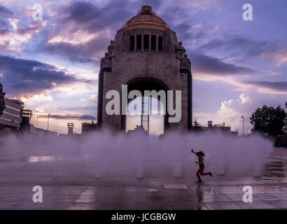 Girl playing with the water fountain in front of Monument to the Mexican Revolution (Monumento a la Revolucion) - Mexico City, Mexico Stock Photo