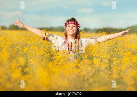 The girl with a big smile in the middle of a blossoming field. It is in the Ukrainian national costume. Stock Photo