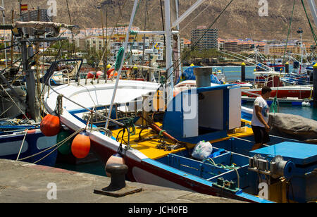 A deck hand works on a local fishing trawler berthed in the crowded harbor in Los Cristianos in Spanish Island of Teneriffe Stock Photo