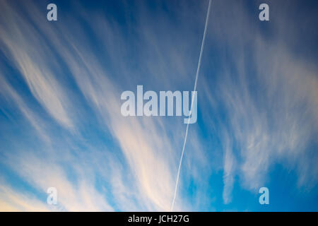 Trace of aircraft in morning sky with clouds. Vapor trail from airline fuel against beautiful cloudscape Stock Photo
