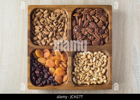Assorted nuts and dried fruits in wooden box. Top view