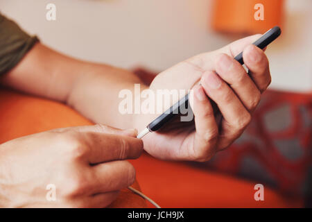 closeup of a young caucasian man plugging a cable to his smpartphone Stock Photo