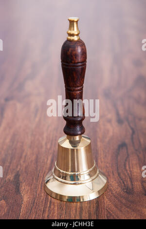 Close-up Of Person Hand On Wooden Table Holding Bell Stock Photo