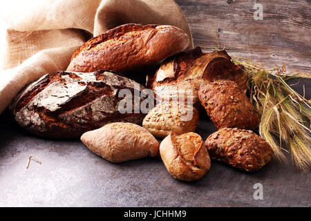 Different kinds of bread and bread rolls on board from above. Stock Photo