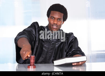 Portrait Of A Male Judge In A Courtroom Striking The Gavel Stock Photo