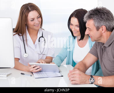 Happy Couple Looking At Digital Tablet Held By Doctor Stock Photo