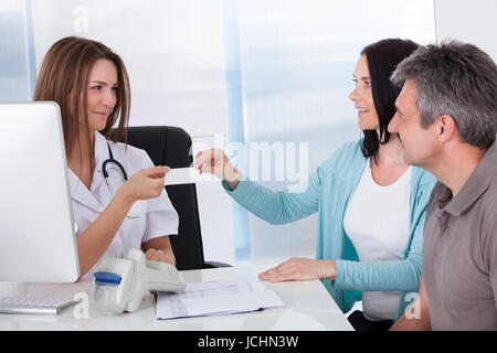 Happy Couple Taking Giving Card From Doctor Stock Photo