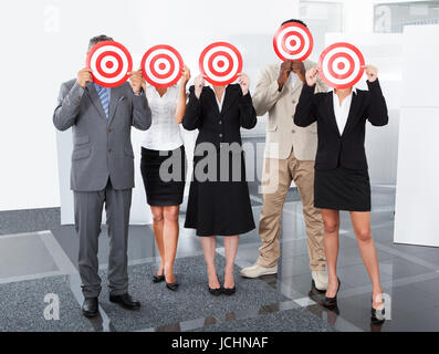 Group Of Businesspeople Holding Dartboard In Front Of Face Stock Photo