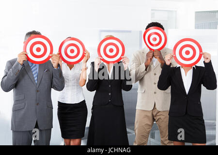 Group Of Businesspeople Holding Dartboard In Front Of Face Stock Photo