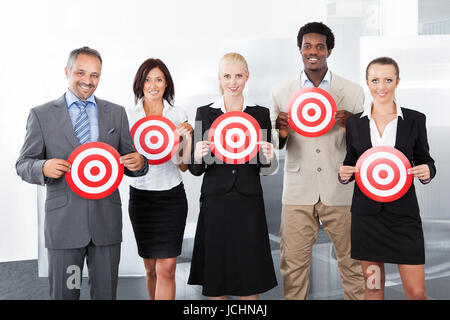 Group Of Businesspeople Holding Dartboard In Front Of Face Stock Photo