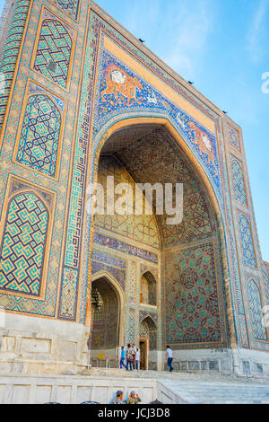 SAMARKAND, UZBEKISTAN - AUGUST 28: Entrance to Sher Dor madrasah of Registan with animals in the mosaic in afternoon sun with people in front of it. S Stock Photo