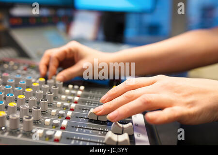 Female Radio Host Using Music Mixer In Studio Stock Photo