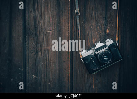 Old gray zenith in a brown leather case hanging on a wooden wall background. Stock Photo