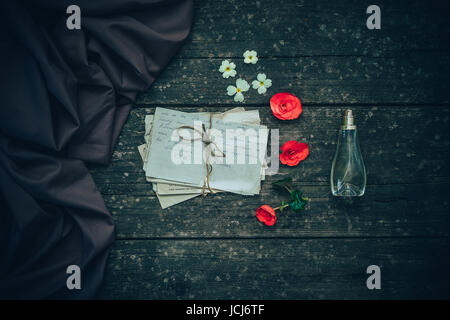 Old letter with elegant ladies ' perfumes and beautiful flowers on wooden background. Stock Photo