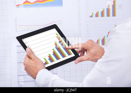 Mature Businessman Analyzing Graph On Digital Tablet Stock Photo