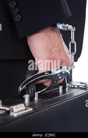 Close-up Of Person Wearing Handcuff Attached To Suitcase Stock Photo