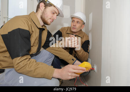 technician metering socket voltage with digital multimeter Stock Photo