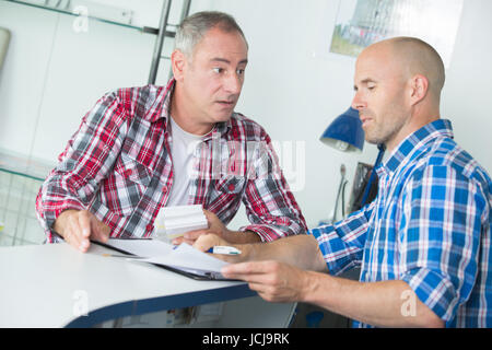 two carpenters are talking while holding papers Stock Photo