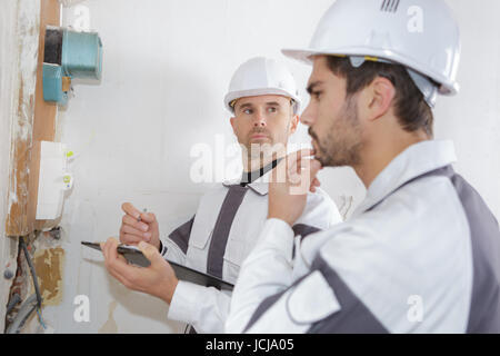 professional electrician installing components in electrical shield Stock Photo