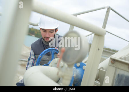 young handsome cement factory worker checking tanker valves Stock Photo