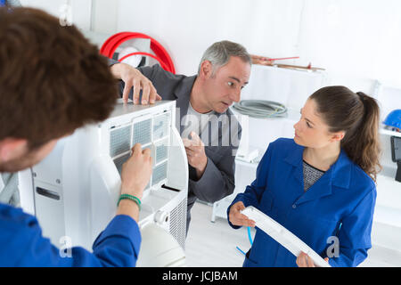 hvac repair technicians working on commercial heating air conditioning unit Stock Photo