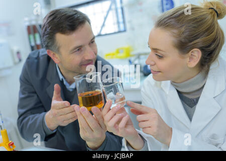 laboratory workers experimenting different liquid in flask containers Stock Photo