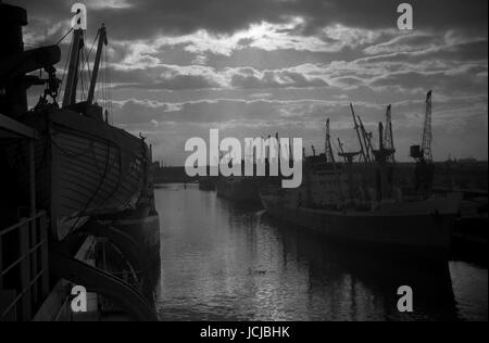 AJAXNETPHOTO. SEPT, 1963. MANCHESTER, ENGLAND. - SUNSET OVER THE DOCKS - VIEW FROM THE DECK OF A CARGO SHIP OF SALFORD DOCKS FILLED WITH SHIPPING. ICONIC LOCATION IN 1961 MOVIE A TASTE OF HONEY. PHOTO:JONATHAN EASTLAND/AJAX REF:509 867 1 Stock Photo