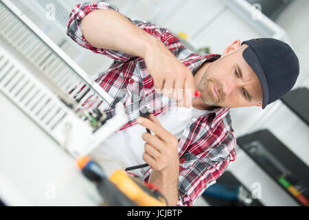 technician installing digital thermostat using screwdriver Stock Photo