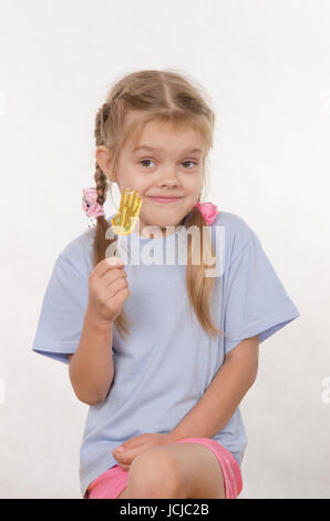 the five-year old girl enthusiastically eats candy Stock Photo