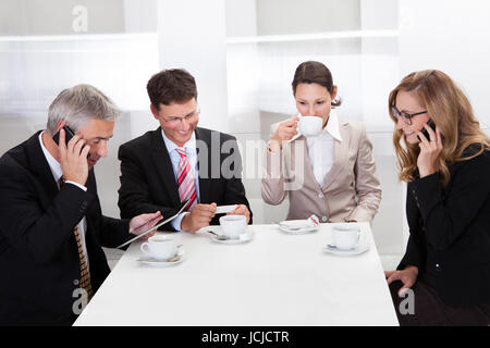 Business executives sitting around a table enjoying a relaxing cup of coffee together during a break Stock Photo
