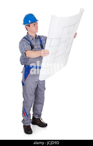 Male construction worker looking at blue prints isolated on white background Stock Photo