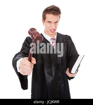 Portrait Of Frustrated Judge Holding Gavel And Book Over White Background Stock Photo