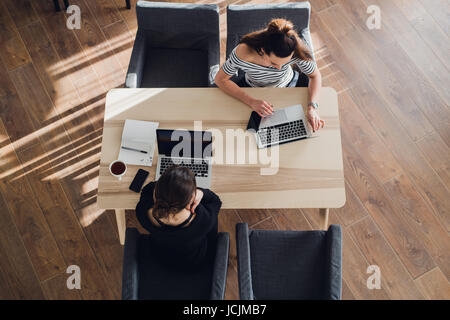 startup business and new mobile technology concept with young couple in modern bright office interior working on laptop and tablet computer on new creative project and brainstorming, aerial top view. Stock Photo