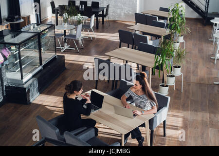 Two women discussing documents in office or cafe. Consultant with woman. Stock Photo