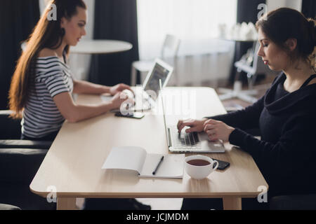 Startup business concept with two young girls in modern bright office interior working on laptops and tablet computers on new creative project and brainstorming, aerial top view. Stock Photo