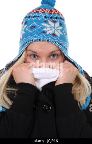 Junge Frau im Winter beim Frieren in der Kälte mit Mütze, isoliert vor einem weissen Hintergrund Stock Photo