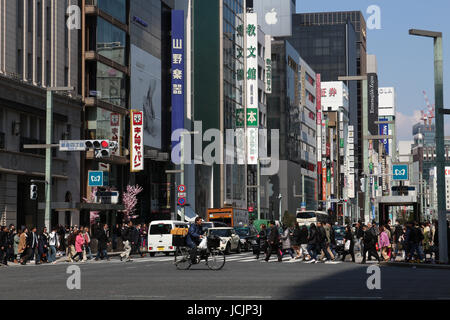Busy street scene in Tokyo, Japan where traffic and pedestrians  vie tor space in this crowded metropolitan capital on a sunny day. Stock Photo