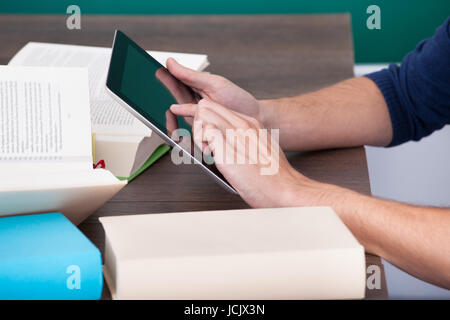 Male Student Surrounded By Books Using Digital Tablet Stock Photo