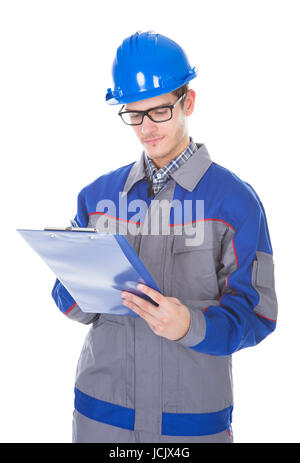 Young Construction Reviewer Wearing Workwear And Hardhat Writing On Clipboard Stock Photo