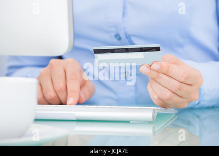 Close-up Of A Person Holding Credit Card Using Computer Stock Photo