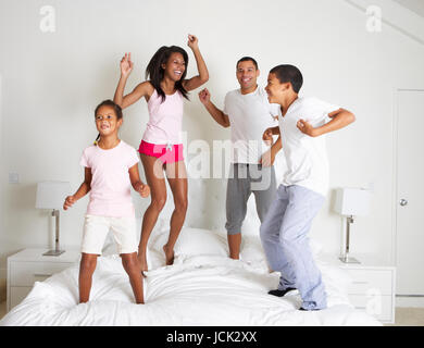 Family Jumping On Bed Together Stock Photo