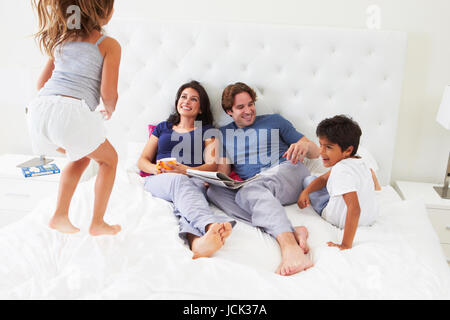 Children Jumping On Parents Bed Wearing Pajamas Stock Photo