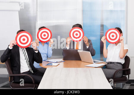 Group Of Businesspeople Holding Dartboard In Front Of Face Stock Photo